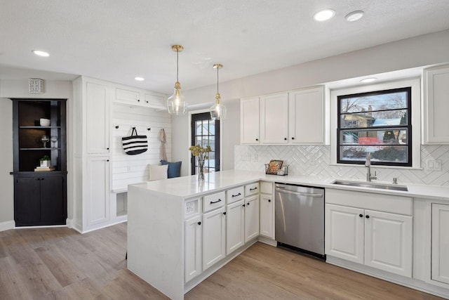 kitchen featuring sink, stainless steel dishwasher, kitchen peninsula, and white cabinets