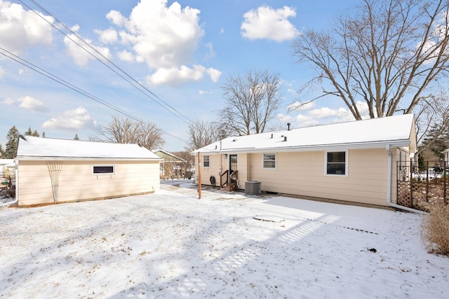 snow covered back of property featuring central AC