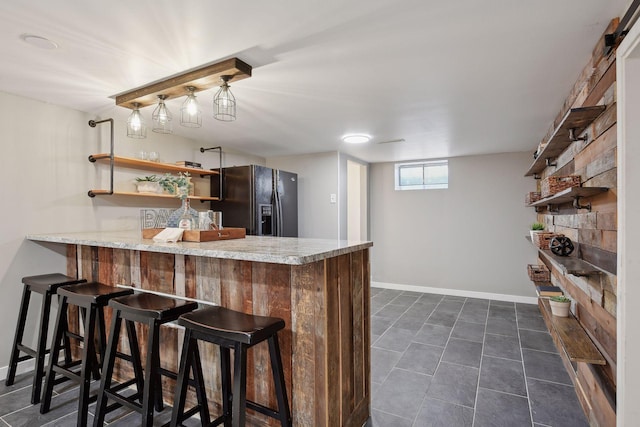 kitchen featuring black fridge, a breakfast bar, kitchen peninsula, and dark tile patterned floors