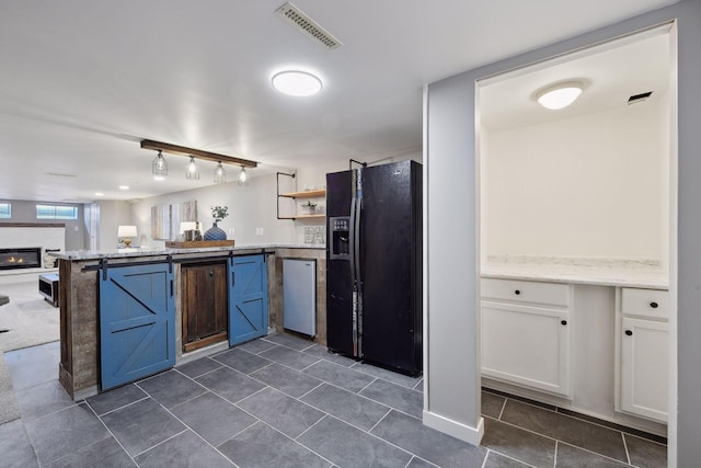 kitchen featuring dark tile patterned floors, white cabinets, refrigerator, and black refrigerator with ice dispenser