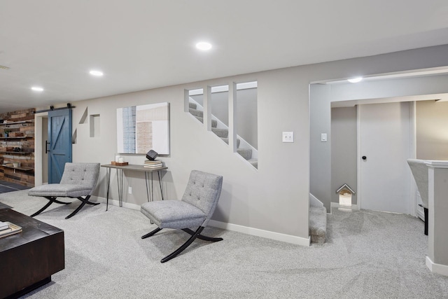 sitting room featuring light colored carpet, a barn door, and a fireplace