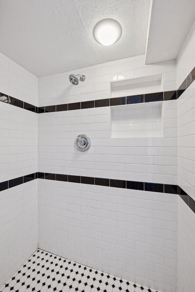 bathroom featuring a textured ceiling and a tile shower