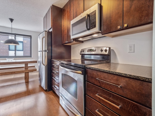 kitchen featuring decorative light fixtures, light hardwood / wood-style floors, a textured ceiling, and appliances with stainless steel finishes