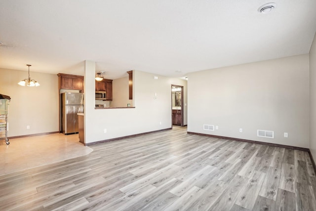 unfurnished living room with light hardwood / wood-style floors and an inviting chandelier