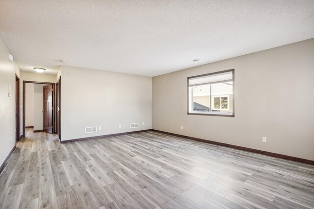 spare room featuring light hardwood / wood-style floors and a textured ceiling