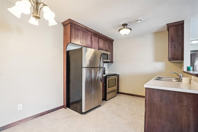 kitchen with a chandelier, a textured ceiling, stainless steel appliances, and sink