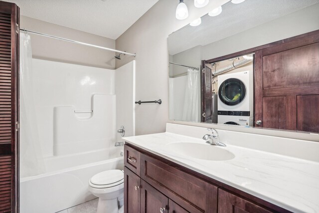 full bathroom featuring vanity, tile patterned floors, toilet, a textured ceiling, and stacked washer / dryer