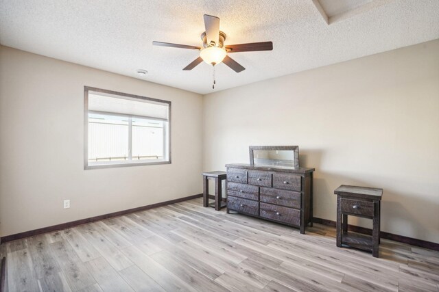 bedroom featuring ceiling fan, light hardwood / wood-style flooring, and a textured ceiling