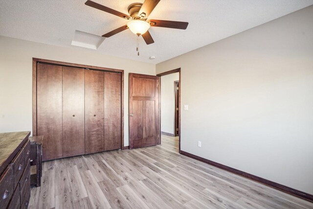 unfurnished bedroom with ceiling fan, light hardwood / wood-style floors, a textured ceiling, and a closet