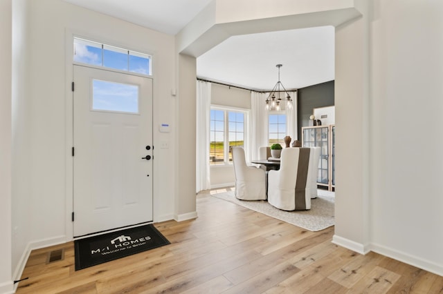 entryway with light hardwood / wood-style flooring and a notable chandelier