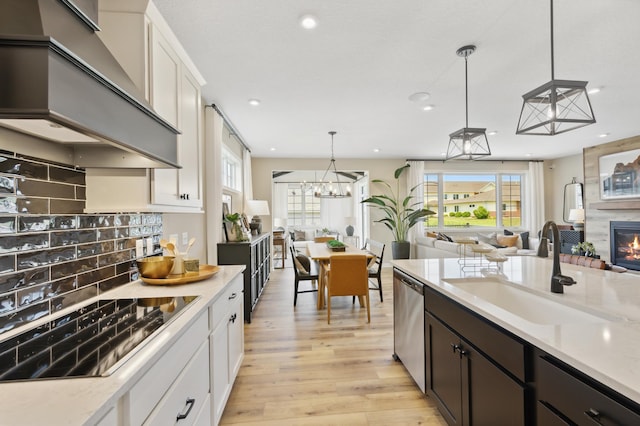 kitchen featuring dishwasher, sink, white cabinets, hanging light fixtures, and black electric cooktop