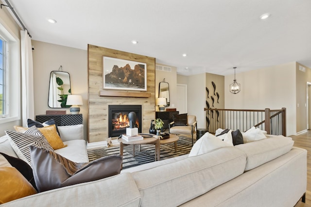 living room with a large fireplace, an inviting chandelier, and light wood-type flooring