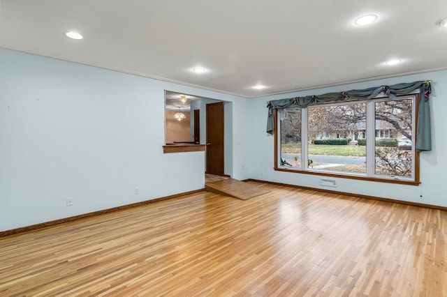 unfurnished living room with ornamental molding and light wood-type flooring