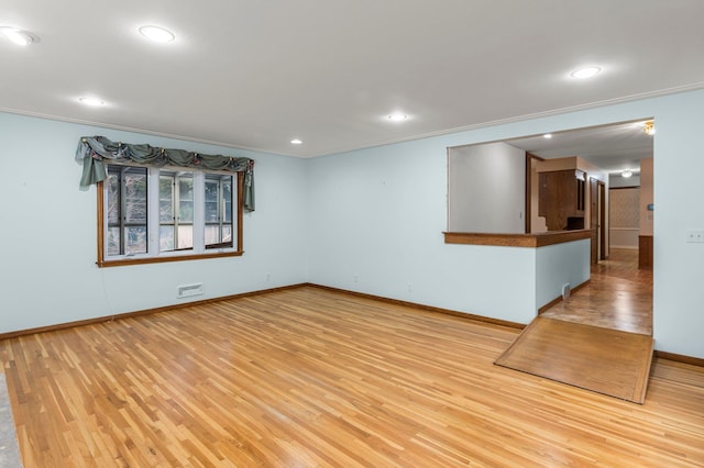 spare room featuring crown molding and light wood-type flooring