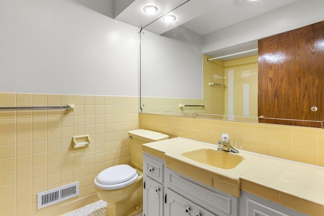 bathroom with tile patterned flooring, vanity, toilet, and tile walls