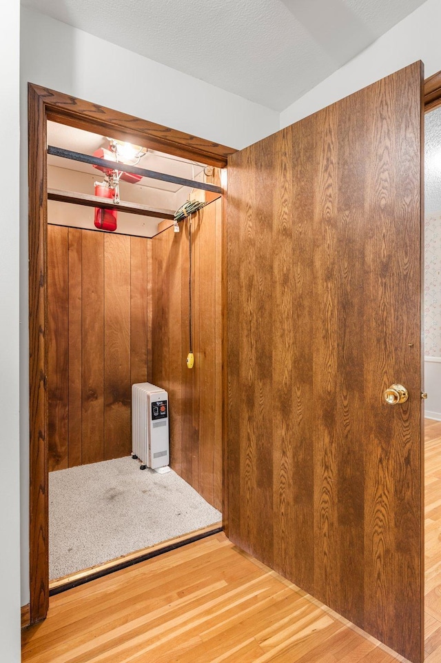 unfurnished bedroom featuring wood walls, a closet, wood-type flooring, and a textured ceiling