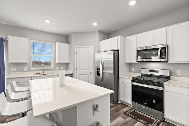 kitchen with dark hardwood / wood-style floors, white cabinetry, sink, and appliances with stainless steel finishes