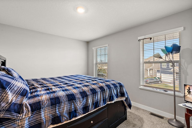 bedroom with light colored carpet and a textured ceiling