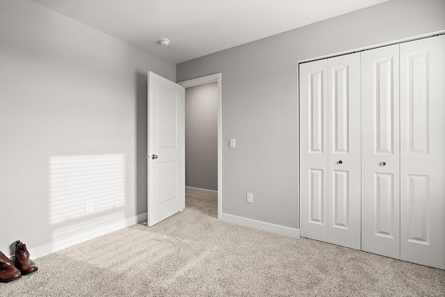 unfurnished bedroom with light carpet and a closet