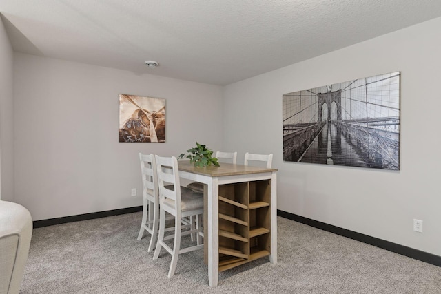 carpeted dining area featuring a textured ceiling