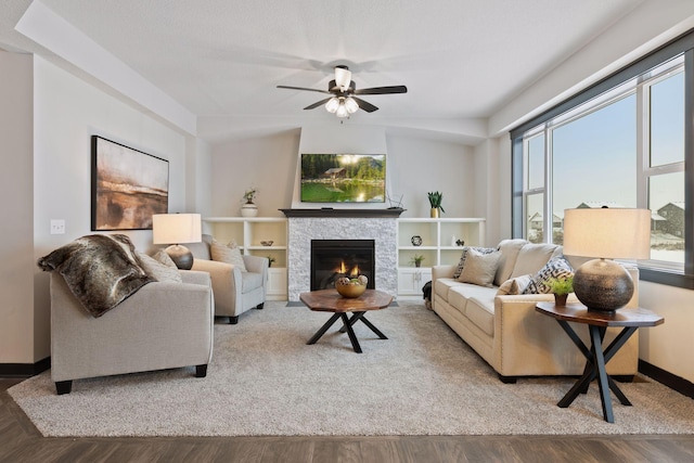 living room with hardwood / wood-style flooring, ceiling fan, and a fireplace