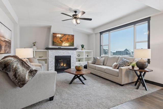 living room featuring a stone fireplace, ceiling fan, and hardwood / wood-style flooring