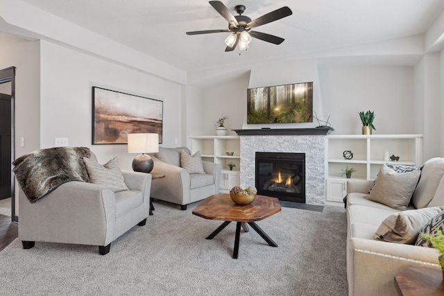 living room with built in shelves, ceiling fan, a fireplace, and carpet