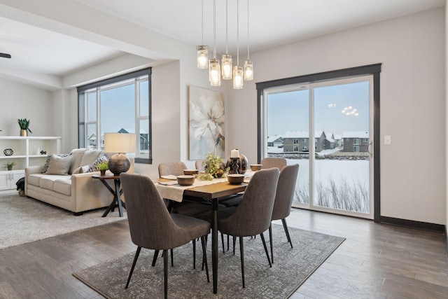 dining space with a wealth of natural light, hardwood / wood-style floors, and an inviting chandelier