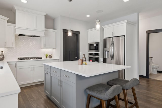 kitchen with backsplash, stainless steel appliances, dark hardwood / wood-style floors, white cabinetry, and hanging light fixtures