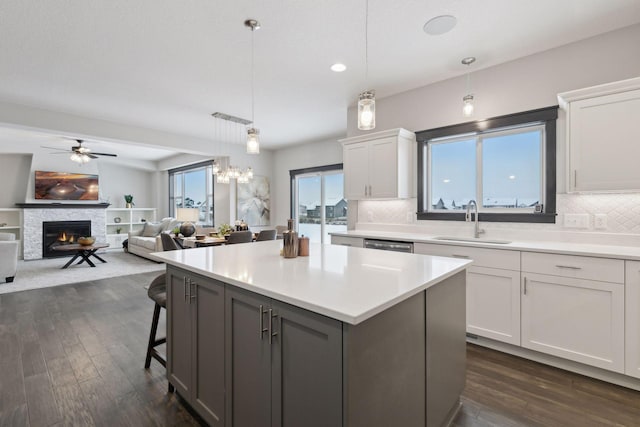 kitchen with white cabinets, sink, decorative backsplash, a fireplace, and decorative light fixtures