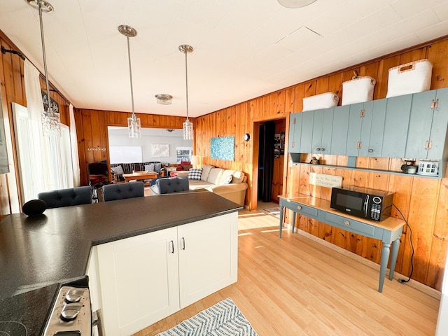 kitchen featuring decorative light fixtures, a healthy amount of sunlight, light wood-type flooring, and wooden walls