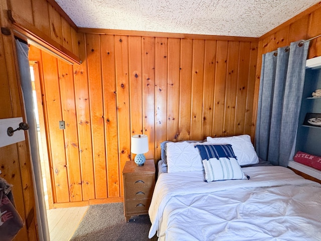 bedroom featuring a textured ceiling, a closet, and wooden walls