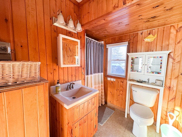 bathroom with tile patterned flooring, toilet, wooden walls, vanity, and a shower with shower curtain