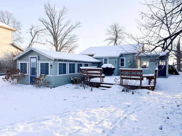 snow covered house featuring a hot tub and a wooden deck