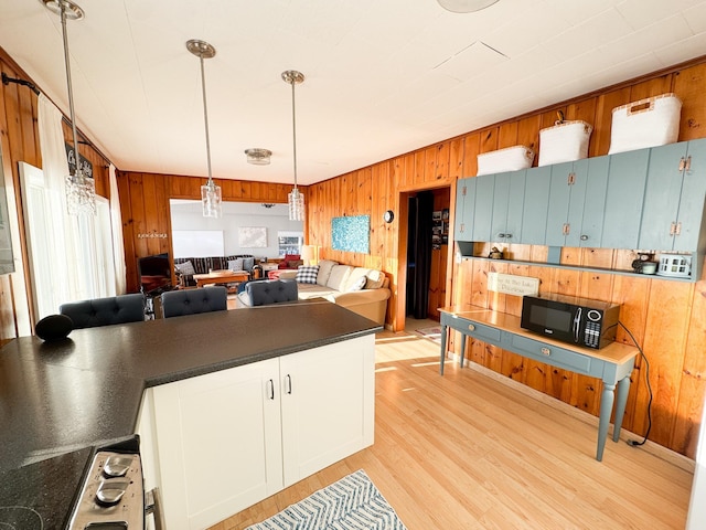 42536 Pleasure Park Rd, Ottertail, MN 56571 - kitchen featuring black microwave, wood walls, dark countertops, light wood-type flooring, and pendant lighting