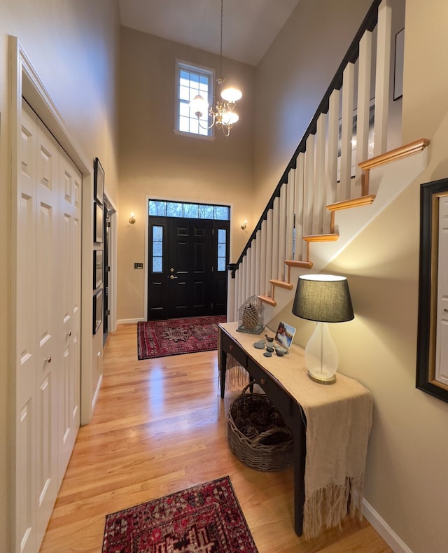 entrance foyer featuring a high ceiling, an inviting chandelier, and light hardwood / wood-style flooring