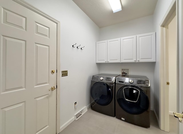 washroom with light tile patterned flooring, cabinets, a textured ceiling, and washing machine and dryer