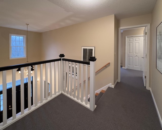 corridor with dark carpet and a textured ceiling