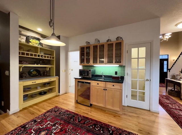 kitchen featuring decorative backsplash, stainless steel appliances, light hardwood / wood-style flooring, a chandelier, and hanging light fixtures