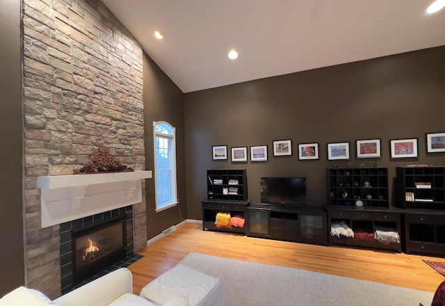 living room featuring a fireplace, high vaulted ceiling, and light hardwood / wood-style flooring