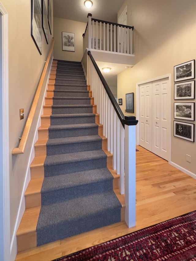 stairway featuring a high ceiling and hardwood / wood-style flooring