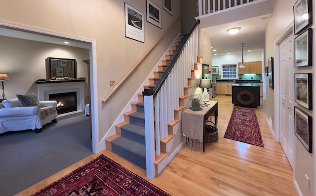 staircase with hardwood / wood-style flooring, wine cooler, and a tiled fireplace