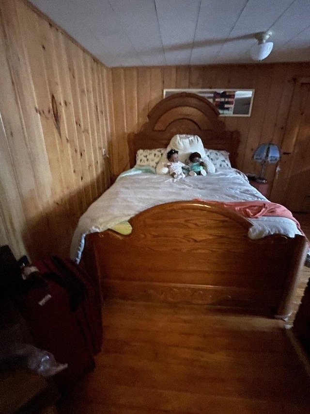 bedroom featuring wooden walls and hardwood / wood-style flooring