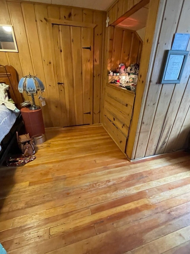 hallway featuring light wood-type flooring and wooden walls