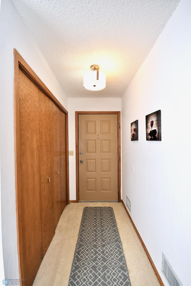 doorway featuring a textured ceiling and light carpet