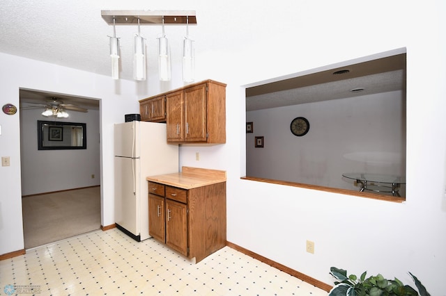 kitchen featuring a textured ceiling, white refrigerator, and ceiling fan