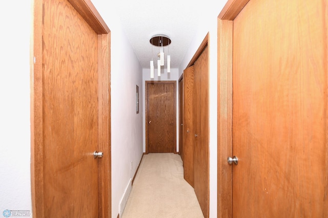 corridor with light colored carpet and a textured ceiling