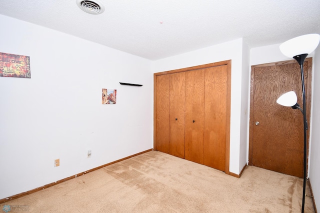 unfurnished bedroom featuring light carpet, a textured ceiling, and a closet