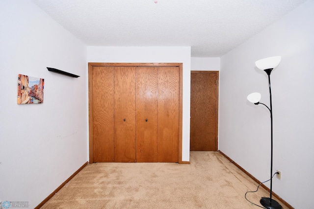 unfurnished bedroom with light carpet, a closet, and a textured ceiling