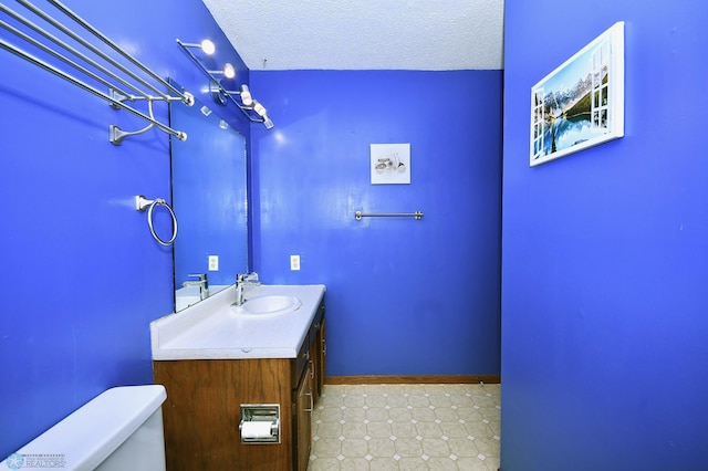 bathroom featuring vanity, a textured ceiling, and toilet